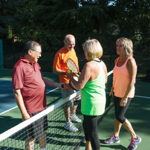 Four fit, active and mature players enjoying the sport and sunshine outside in healthy community.