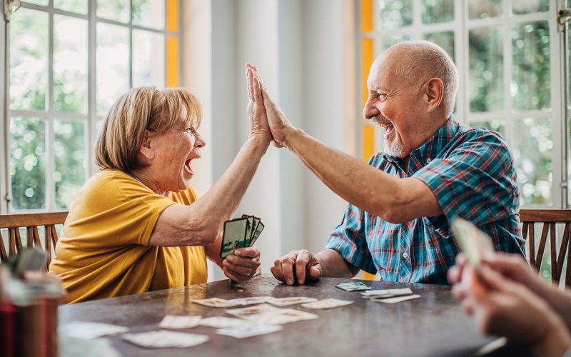 Man and woman, senior couple playing cards in nursing home.